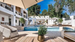 A modern outdoor pool area with a wooden deck, lounge chairs, and a potted plant. - Contemporary Golf Villa Las Brisas Nueva Andalucia (Marbella)