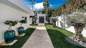 A modern house with a paved walkway, white walls, and a black gate. - Contemporary Golf Villa Las Brisas Nueva Andalucia (Marbella)