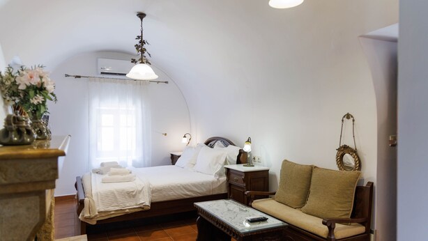 Een slaapkamer met een bed, nachtkastje, lamp en een bank.