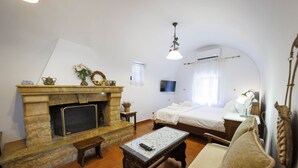 Een gezellige woonkamer met een stenen open haard, een comfortabele bank, een salontafel en een bed met een witte spreidek.