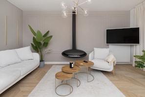 Un salon moderne avec un canapé blanc, une table basse ronde, une table d’appoint, une plante en pot, un meuble TV noir et un luminaire suspendu au plafond.
