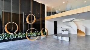 Eine moderne Lobby mit runden Leuchten, einer Treppe und einem Empfangsbereich.