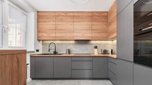 Eine moderne Küche mit grauen Schränken, einer Holz Arbeitsplatte und einer Edelstahl-Dunstabzugshaube.