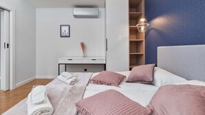 Ein modernes Schlafzimmer mit Bett, Nachttischen, einem Kleiderschrank und einer Wand-Klimaanlage.