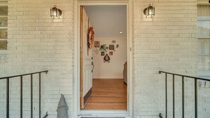 A staircase leading to a room with a white brick wall, two wall-mounted lanterns, and a wooden floor. - Restful Haven Near Savannah - King Bed (Pooler)