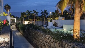 A pathway flanked by a stone wall and lush greenery, leading to a building entrance. - Comfort and exclusivity on the tropical coast (Motril)