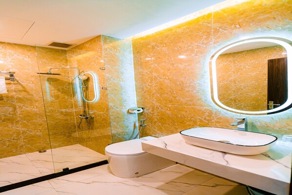 A modern bathroom with a glass-enclosed shower, a white toilet, and a marble vanity with a sink.