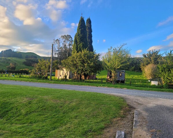 Un paysage rural avec une route, des champs verdoyants et quelques petits bâtiments.