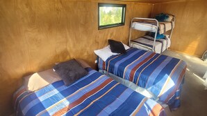Een gezellige kamer met twee bedden, een stapelbed, houten wanden en een klein raam.