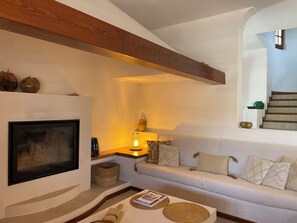 Ein Wohnzimmer mit Kamin, einer Couch, einem Couchtisch und einer Treppe.