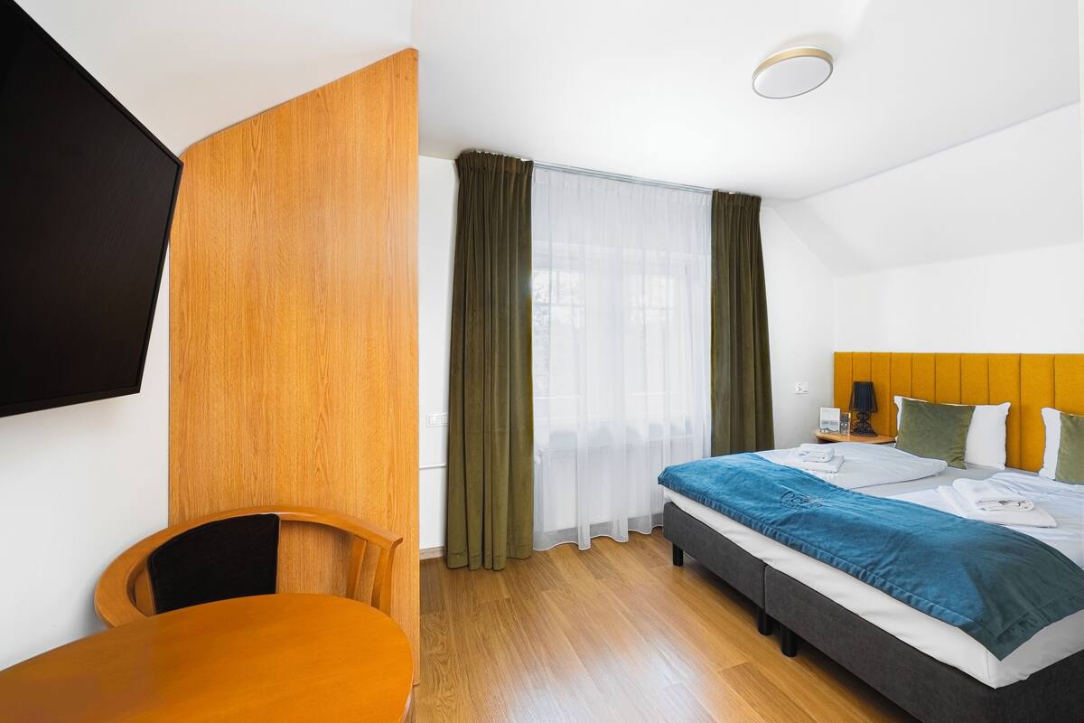 Quarto de hotel com cama, escrivaninha e uma cadeira.