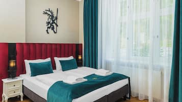 Una habitación de hotel con una cama, una mesita de noche, una lámpara y una ventana con cortinas.