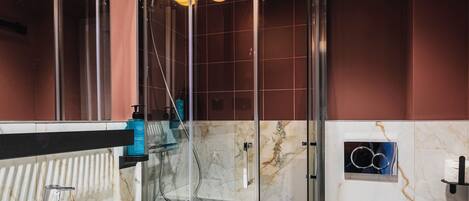 A modern bathroom with a glass-enclosed shower, a marble sink, and a white toilet.