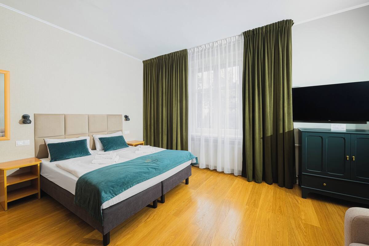 Quarto de hotel com cama, televisão, guarda-roupa e secretária.