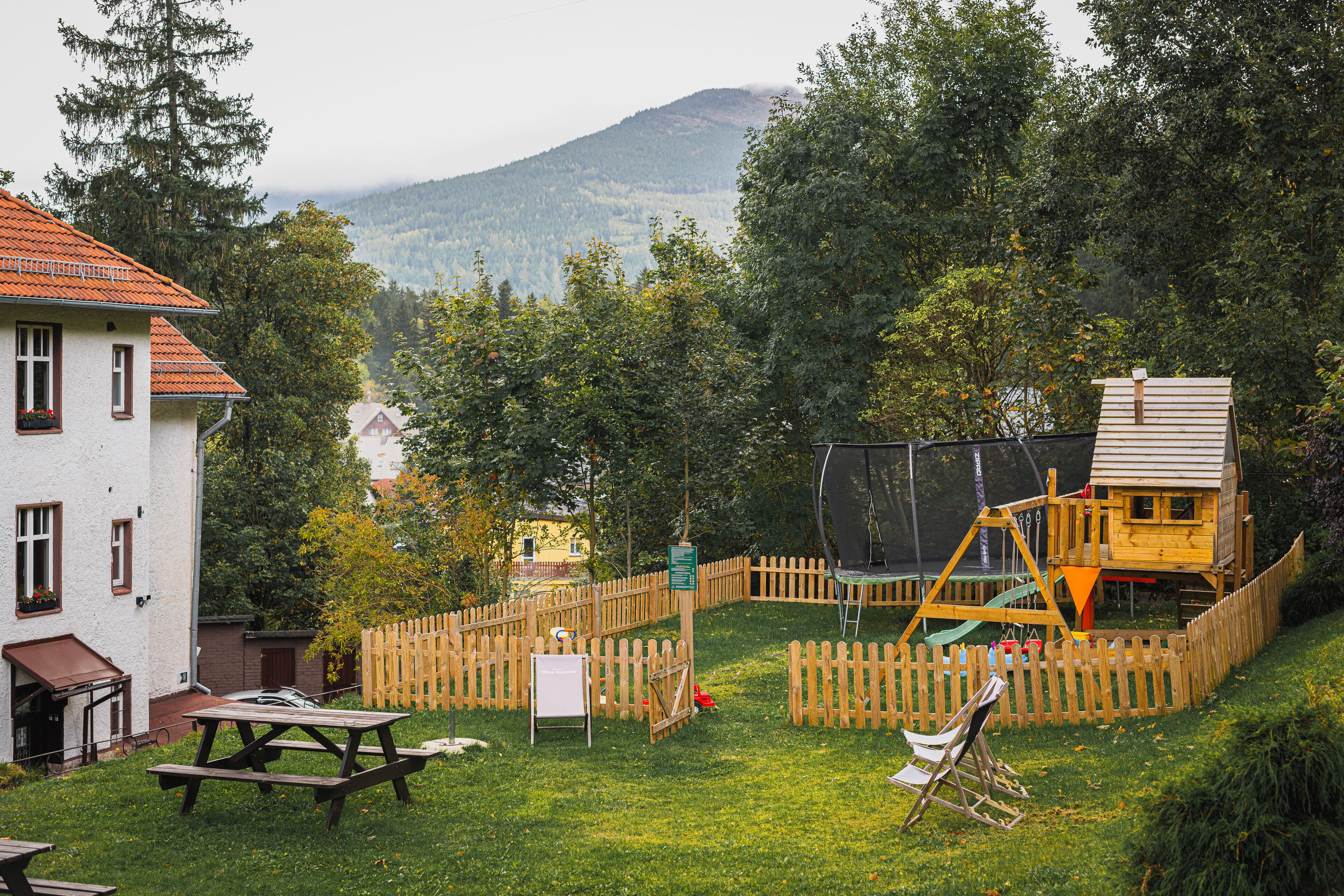A backyard with a wooden playhouse, picnic table, and a swing set.