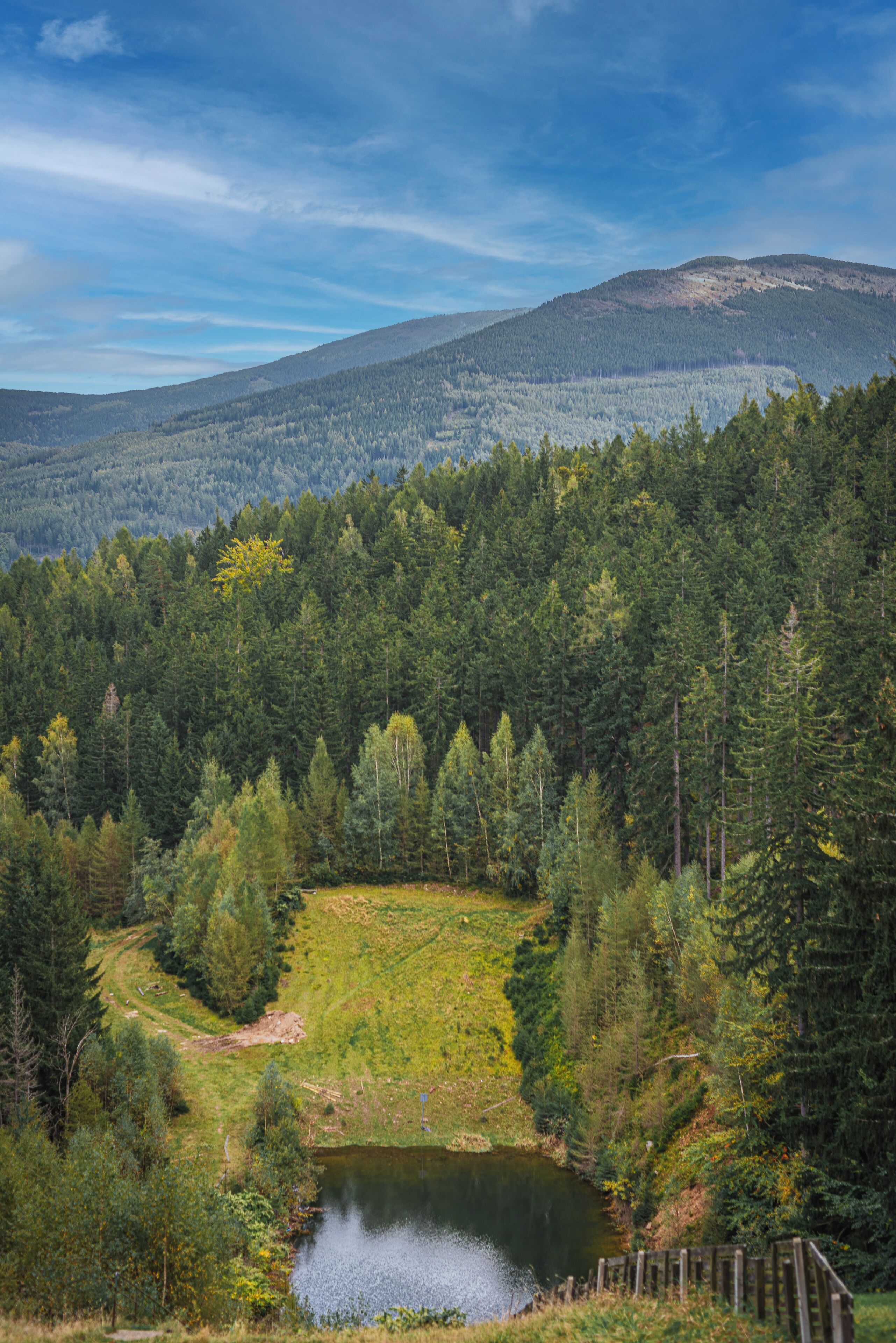 A mountainous landscape with a lake, forested area, and a clear sky.