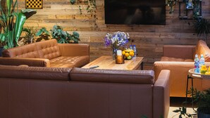 Un salón acogedor con sofás de cuero, una pared de madera, un televisor de pantalla plana y diversas plantas.