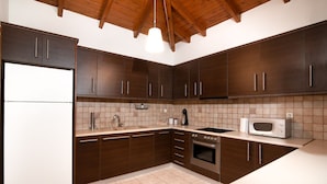 A modern kitchen with dark wooden cabinets, a white refrigerator, a sink, a stove, and a microwave. - MTC-NS Apartments by the Airport (Markopoulo Mesogaias)