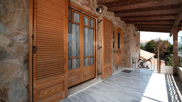 A covered outdoor area with stone walls and wooden doors. - MTC-NS Apartments by the Airport (Markopoulo Mesogaias)
