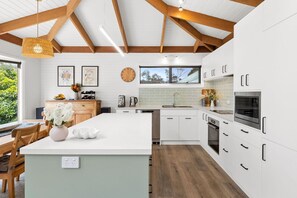Una cocina moderna con armarios blancos, una isla grande y techo de madera.