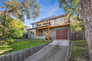 A two-story house with a front porch, a garage, and a landscaped yard.