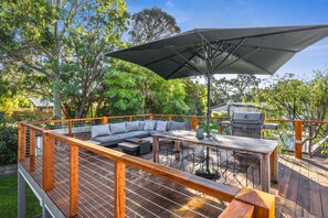 Una terraza de madera con un sofá integrado, una mesa y una parrilla.