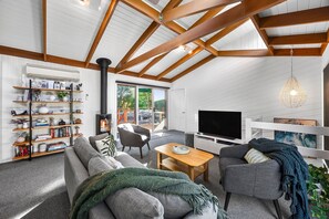 Uma sala de estar moderna com teto alto, estantes embutidas, lareira, televisão e um espaço de estar aconchegante.