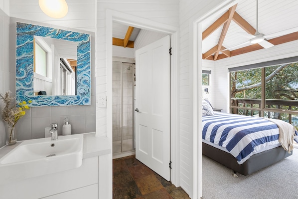 A bedroom with a bed, a bathroom with a sink, and a shower.