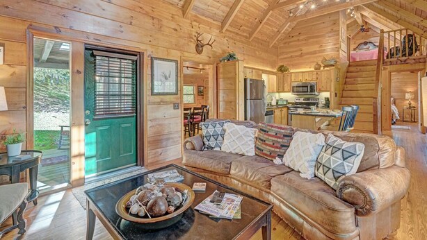 Ein gemütliches Blockhaus mit Holzvertäfelung, einem Essbereich, einer Küche und einem Wohnzimmer mit einer Ledersofa.