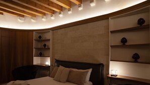 A hotel room with a bed, a chair, and shelves with decorative items. - Palazzo Vittoria (Bisceglie)