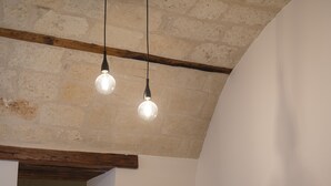 A modern room with a dark-colored sofa, a wooden ceiling, and a bed in the background. - Palazzo Vittoria (Bisceglie)