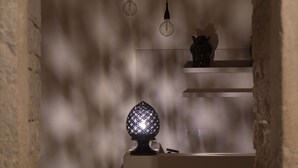 A dimly lit room with a modern kitchen area, featuring a white countertop, a black chair, and a decorative light fixture. - Palazzo Vittoria (Bisceglie)