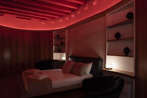 A modern bedroom with a bed, bedside tables, and a chair. - Palazzo Vittoria (Bisceglie)