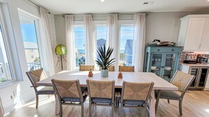 A dining area with a large table, six chairs, and a potted plant. - Gone Coastal: A Paws-itively Perfect Beach Escape! (Surf City)