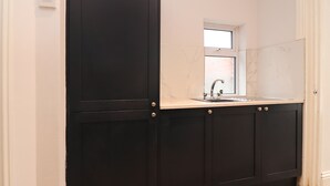 A kitchen with dark cabinets, a window, and a sink. - 37 Nutter Road (Thornton-Cleveleys)