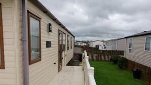 En rad med husvagnar, alla med en träveranda och en inhägnad trädgård.