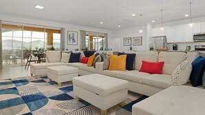 Una sala moderna con un conjunto de sofá, otomanas y una alfombra estampada.