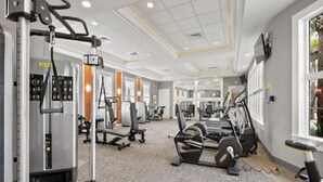 Un gimnasio amplio con diversas máquinas de ejercicio, incluyendo una banca de pesas y equipamiento cardiovascular.