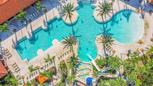 Vista aérea de un resort con múltiples piscinas, palmeras y zonas de descanso.