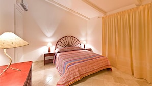 A bedroom with a bed, bedside lamps, a lamp on a table, and a curtain. - Apartment with beautiful sea view (Santa Teresa Gallura)