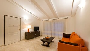 A living room with a sofa, a coffee table, a TV, and a cabinet. - Apartment with beautiful sea view (Santa Teresa Gallura)