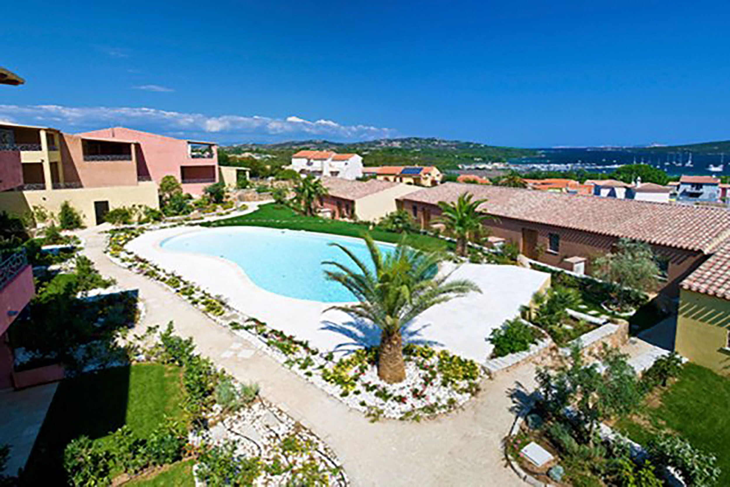 Ein Resort mit Pool, umgeben von Palmen und Blick auf das Meer.