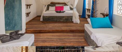 A room with a bed under a canopy, a wooden floor, and a view of an outdoor area with a chair and a table.
