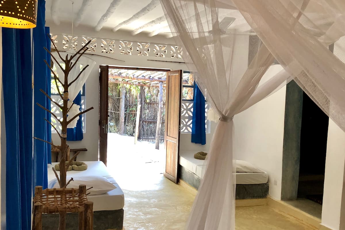 A room with a bed, a small table, and a window with blue curtains.