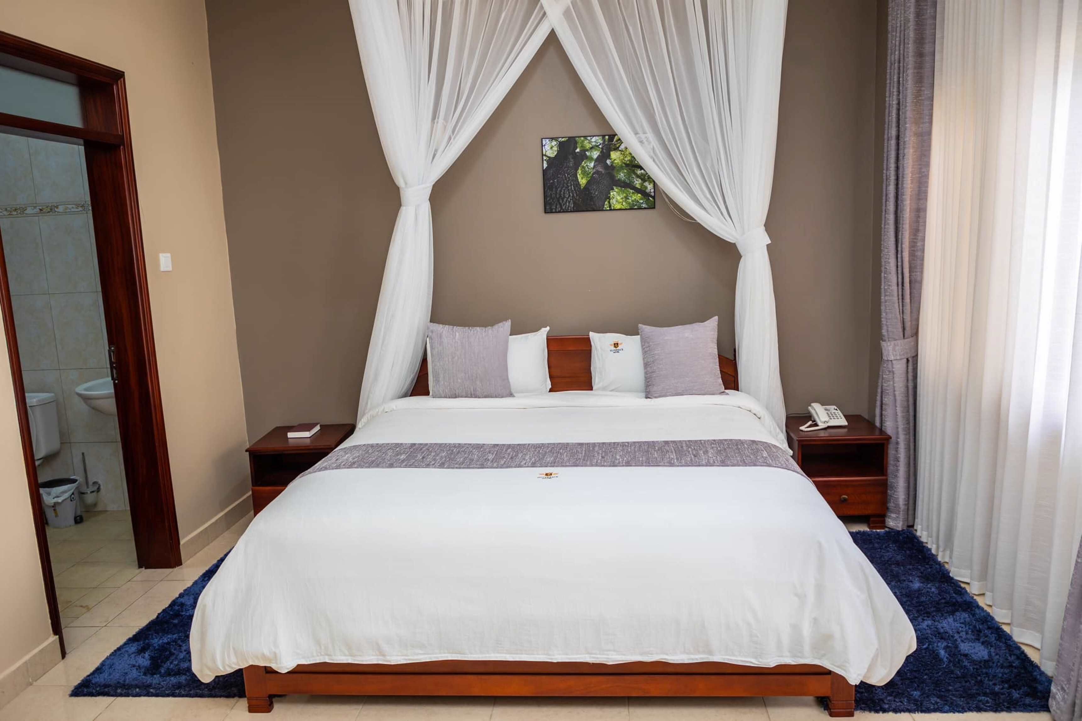 A neatly made bed with a white bedspread and pillows, a wooden headboard, and a bedside table with a phone.