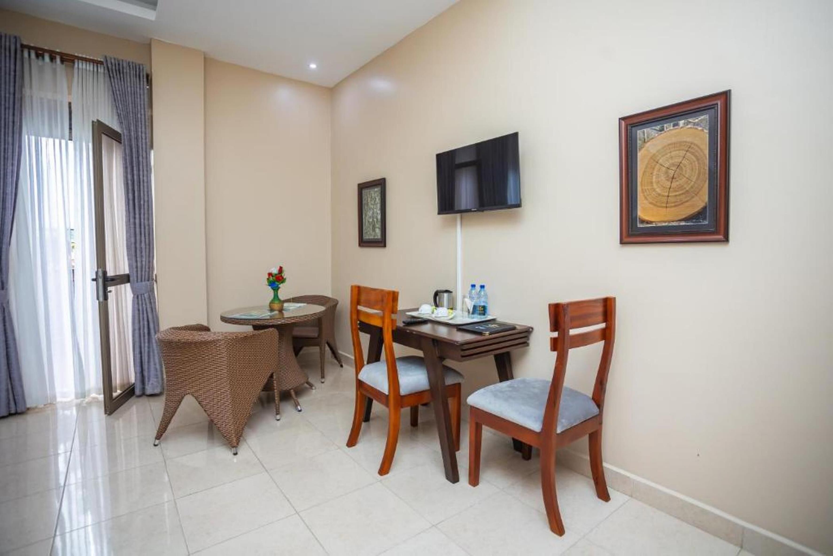 Habitación de hotel con comedor, televisor montado en la pared y una obra de arte enmarcada.