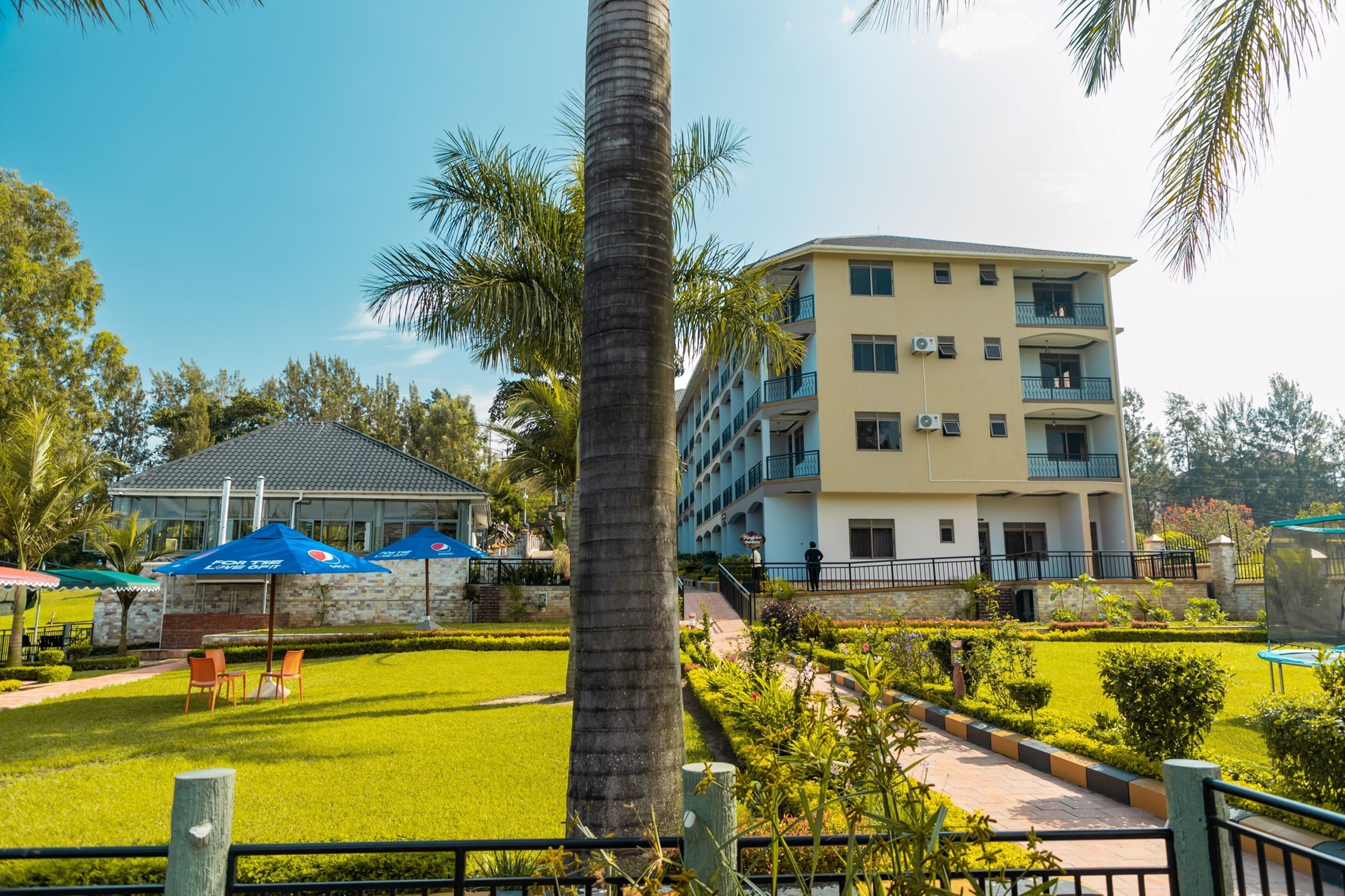 A hotel with a multi-story building, outdoor seating area, and a well-maintained garden.