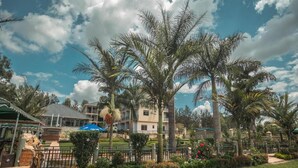 Un patio de hotel con palmeras, un camino y un edificio con balcones.