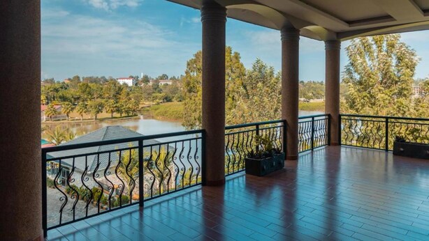 Un espacio al aire libre techado con columnas, vista a un lago y baranda.