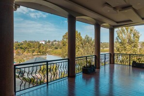 A covered outdoor area with columns, a view of a lake, and a railing. - Silverback Hotel (Mbarara)